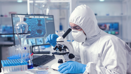 Laborant die een microscoop gebruikt